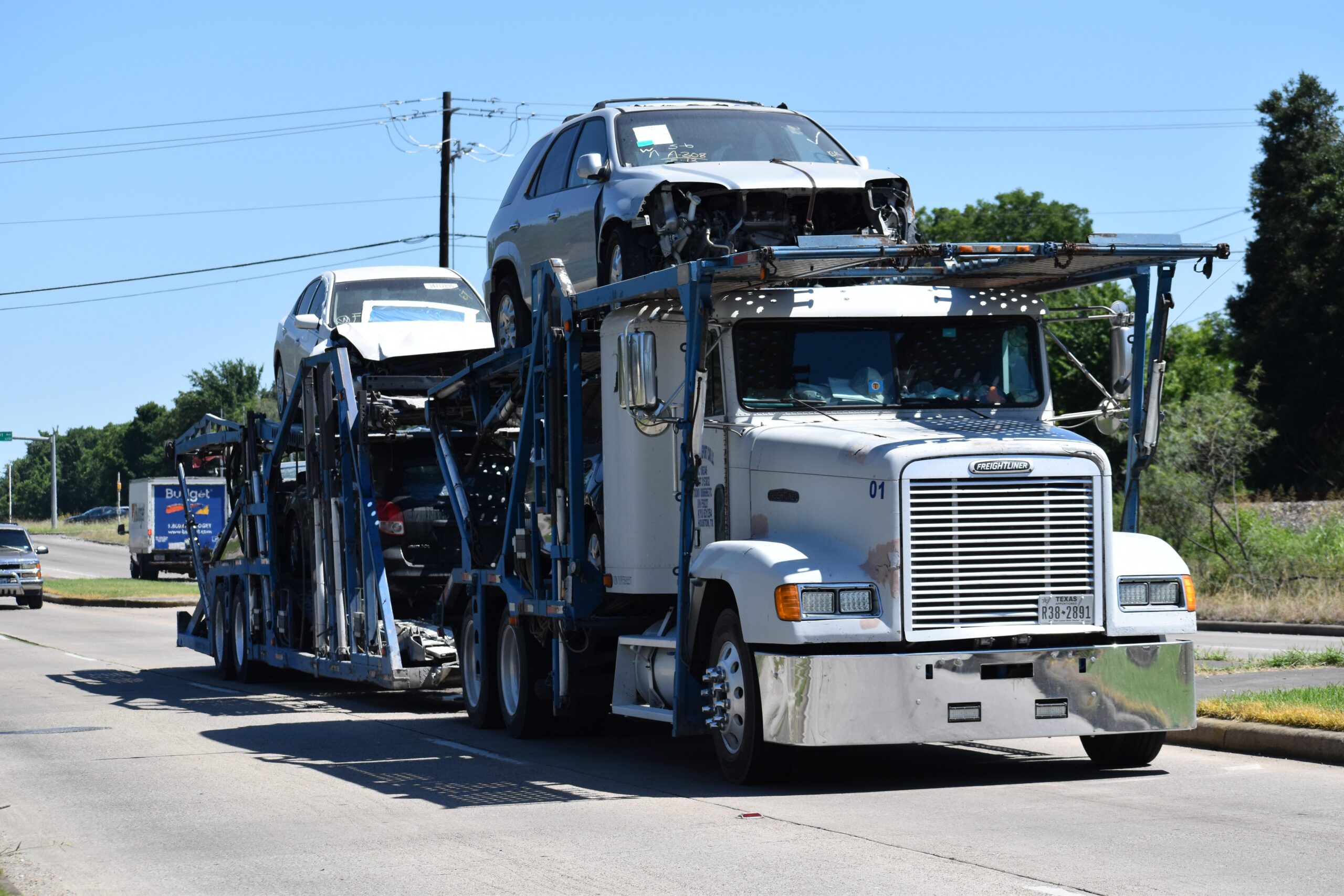 Tow-truck with two totaled cars on bed