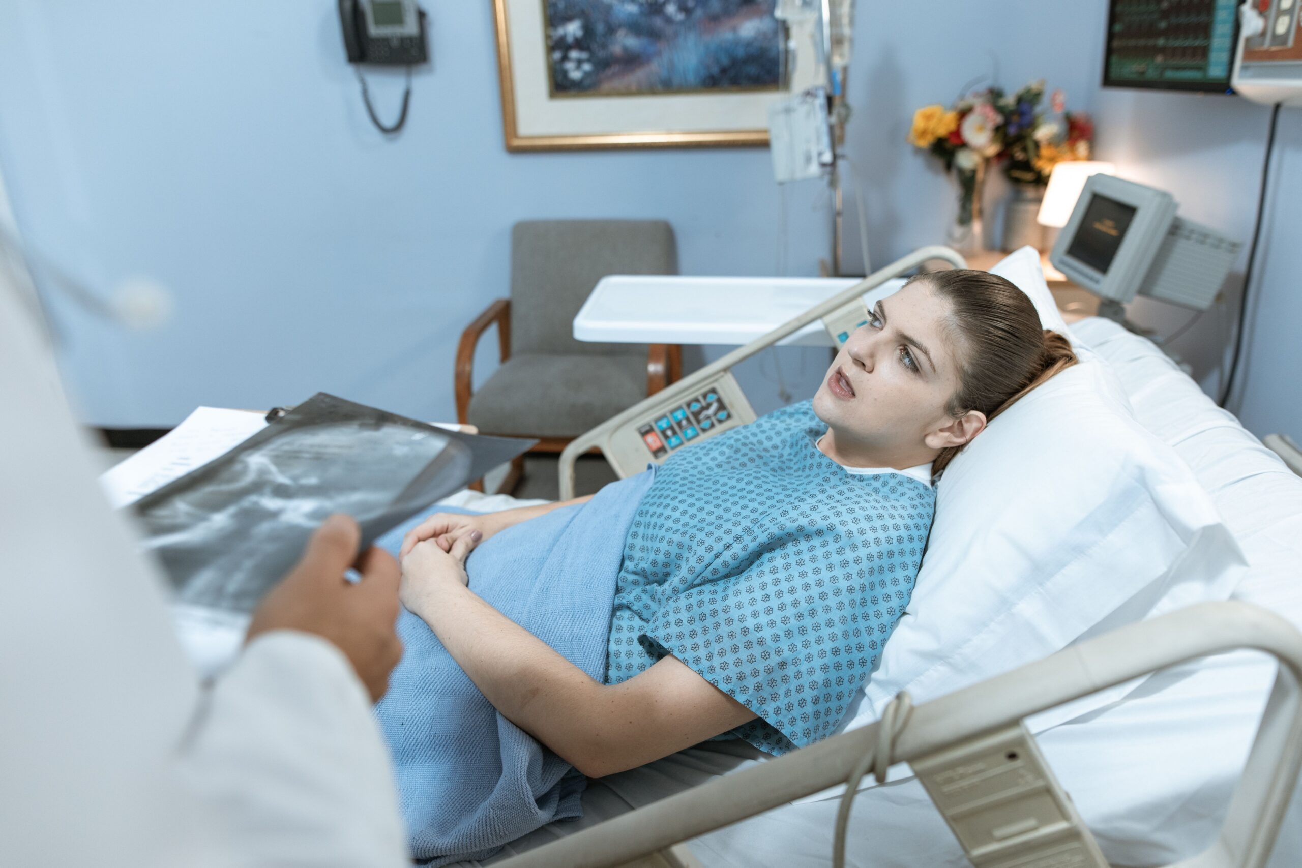 Woman in hospital bed consulting with a doctor by her bedside